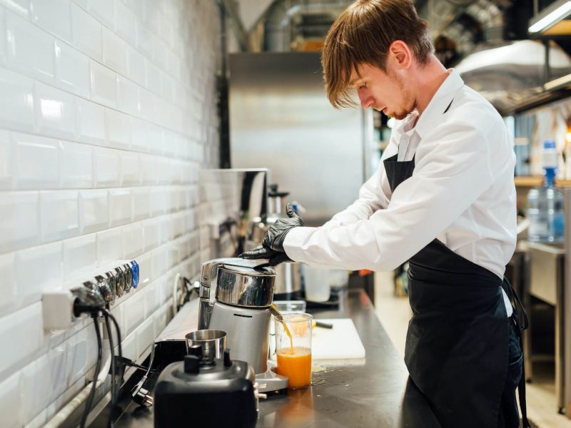 a-cafe-worker-makes-orange-juice-in-a-juicer-catering-kitchen-work-.jpg